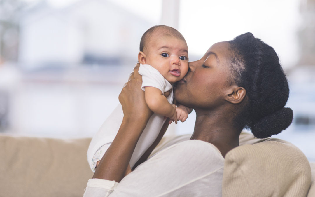 Beautiful African American mother holds newborn baby in the living room