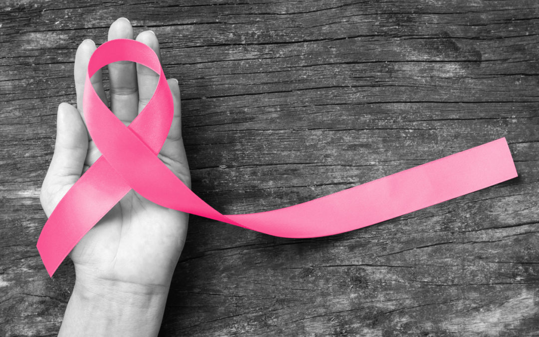 Pink ribbon awareness symbol on woman hand: raising awareness campaign on female people living with breast cancer