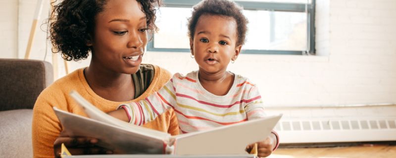 Mom and toddler reading a book together